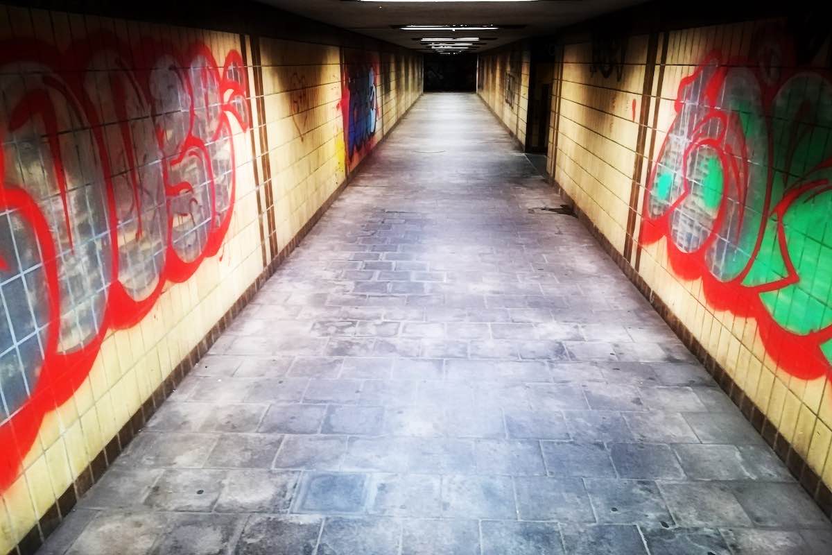 Ein Tunnel unter einem Bahnhof mit sehr viel bunten Graffities an den gekachelten Wänden rechts und links. © Tom Rübenach