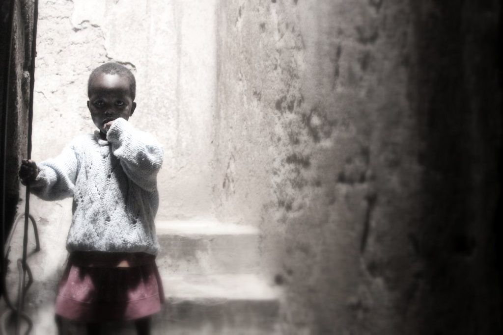 Ein kleines Kind, vielleicht drei Jahre alt, in einem Treppenhaus, das verängstigt schaut. © Tom Rübenach