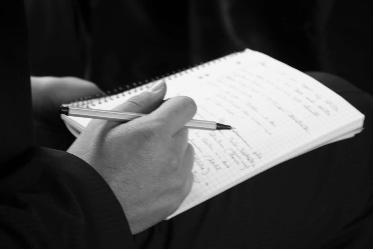 Eine Hand und ein großes Notizheft © Tom Rübenach