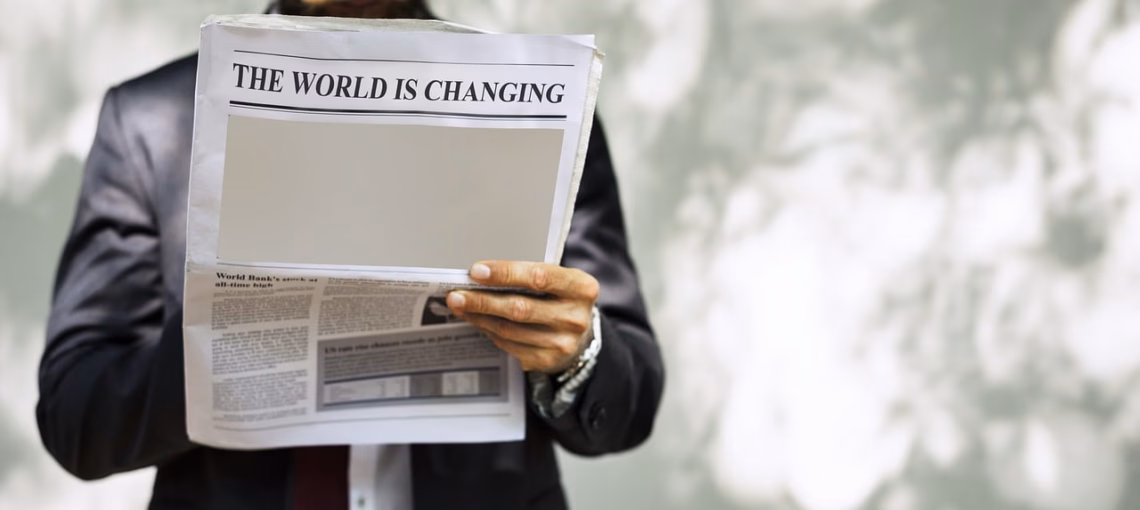 Ein Mann liest eine Zeitung, auf der statt eines Leitartikels ein weißer Fleck zu sehen ist. Die Schlagzeile lautet "The world is changing".